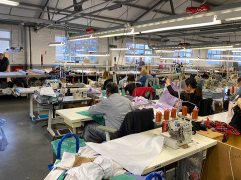 Our ethical factory, Apparel Tasker, in East London. Image shows the back of the machinists sewing the shirts, in a bright open space in the factory. Everyone here is paid well above the living wage, whilst the factory have a policy of allowing the necessary time to make. Nothing is rushed, and the quality is beautiful.