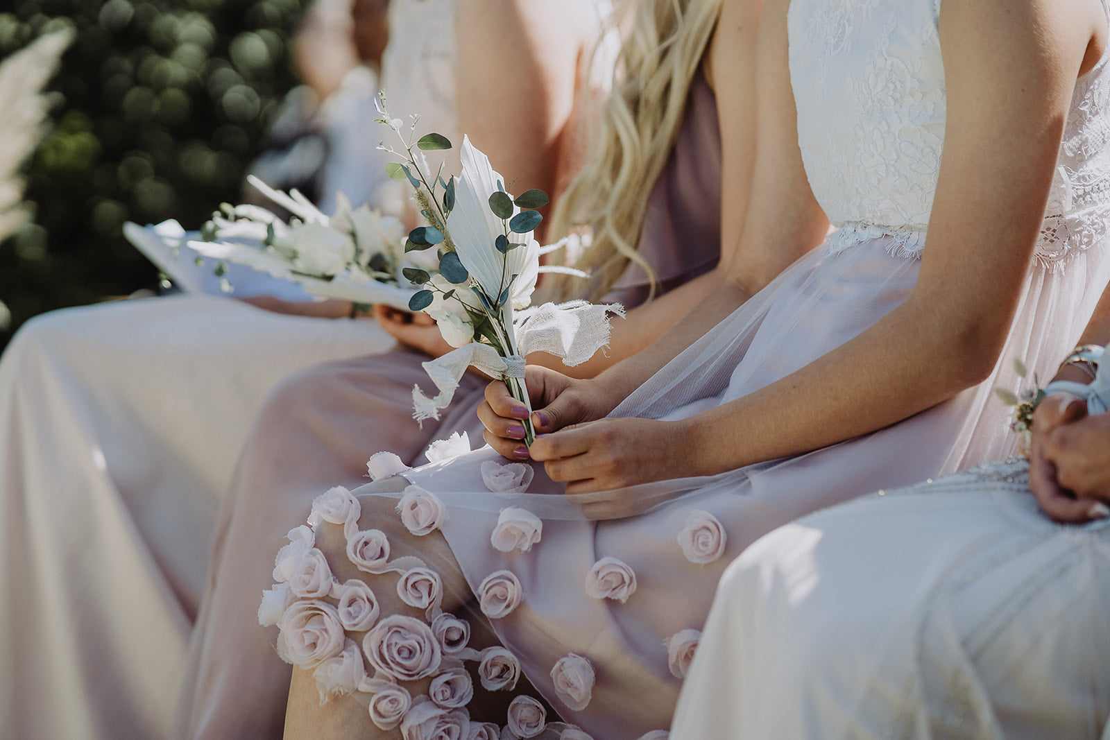 The Bridesmaid holds her flowers in hand. Her dress is embellished with fabric roses.