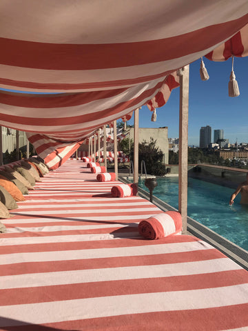 Soho House Barcelona roof top pool with red and white stripe sun lounging beds