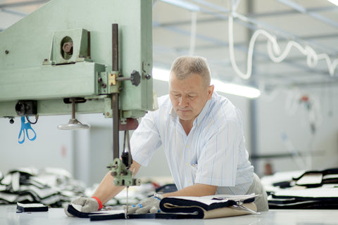 Saywood Blog - Mantra cutter cutting the garment panels on the saw machine wearing protective gloves.