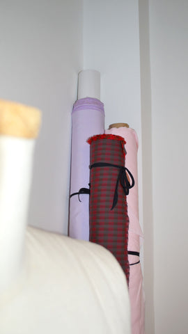 Saywood fabric rolls can be seen leaning against a wall, with the top of a dress making stand in the foreground.