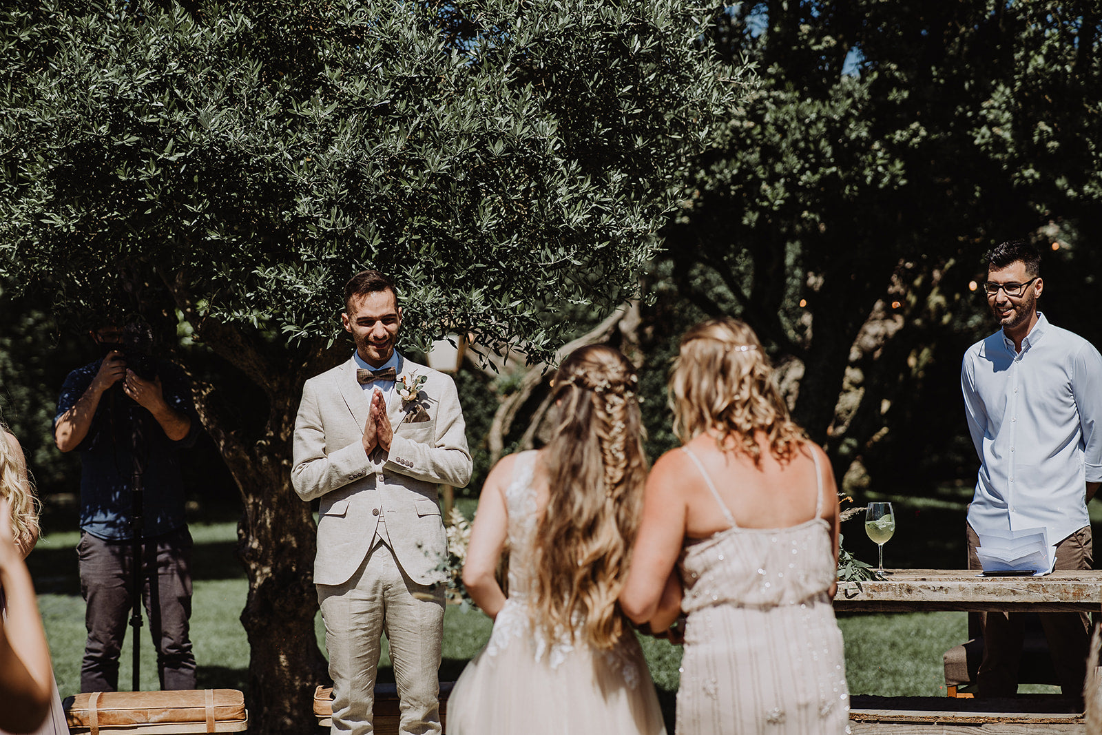 Sustainable Wedding isle, bride walks towards the groom with the mother of the bride. Groom stands under trees watching the bride come towards him.