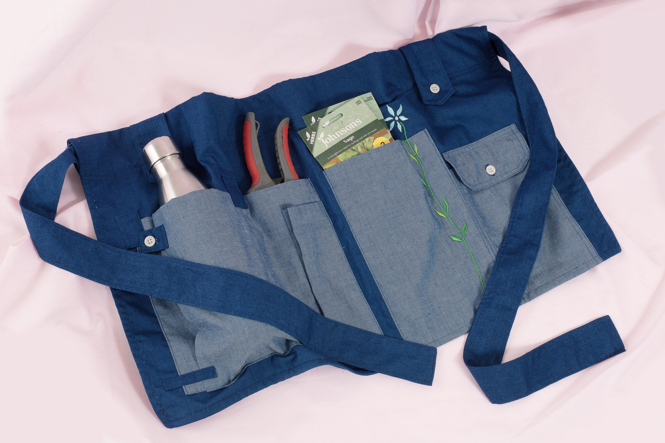 Multifunctional Gardener's Tool Belt made from 100% Japanese denim dyed with natural indigo, by Saywood. Tool belt has gardening tools tucked into the pockets.