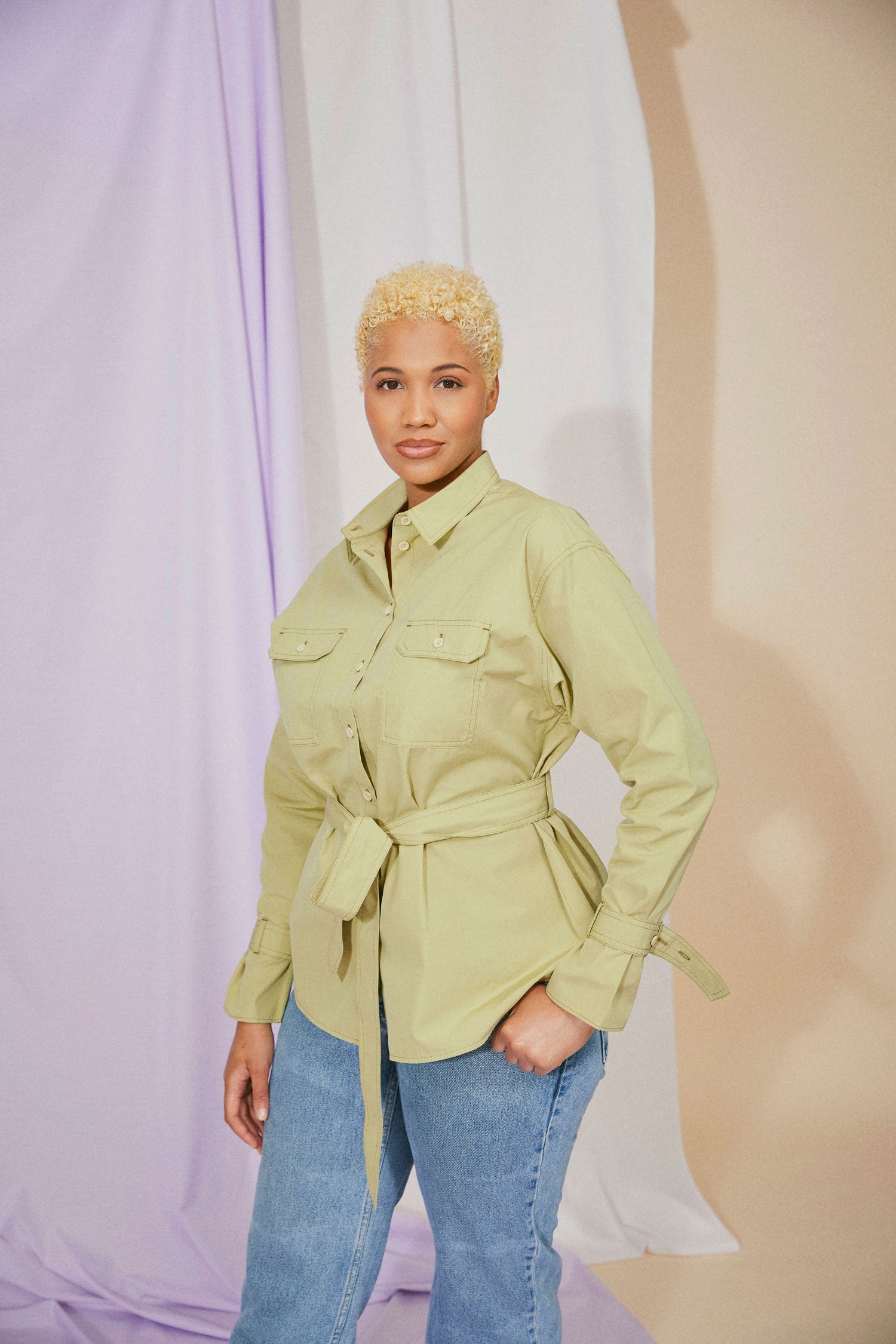 Womens olive green shirt: Saywood Zadie Boyfriend Shirt in olive deadstock cotton. Model has the belt tied round her waist with her hand in her pocket.