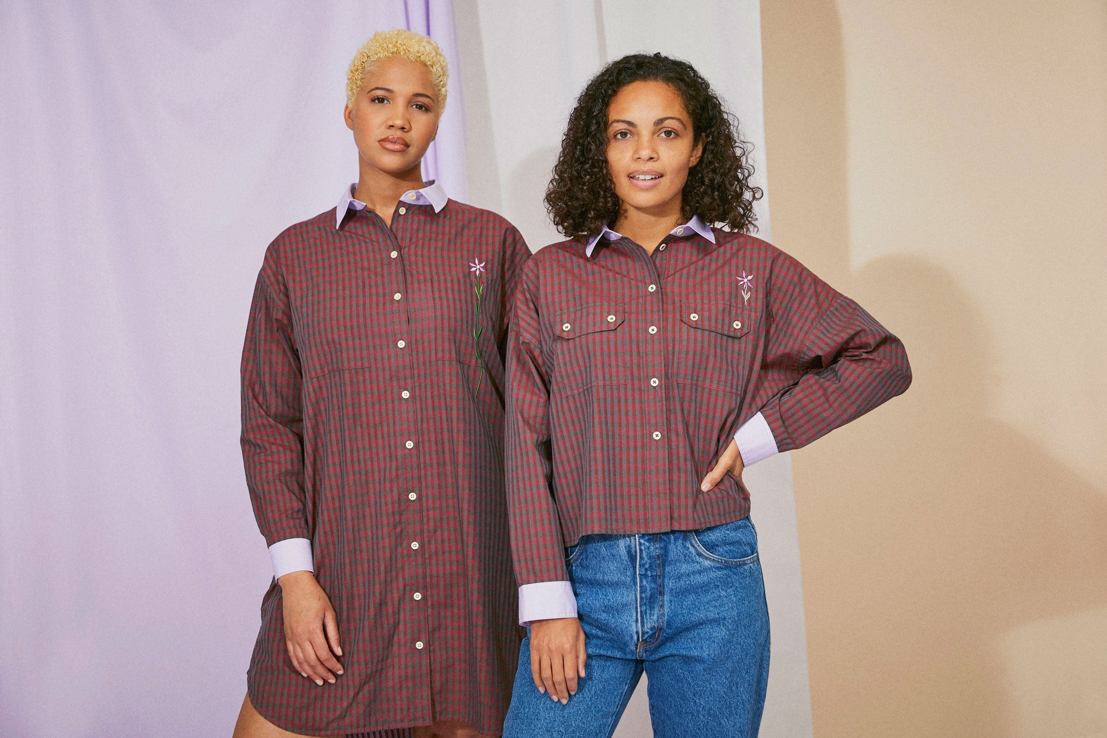Two model stand side by side. The woman on the left wears Saywood's red check Etta Oversized Shirtdress. The woman on the right wears the Jules red check utility shirt, worn with jeans.
