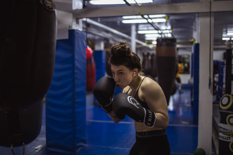 Arianna focused while working on a heavy bag with her RSLNT gloves on