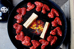 Angus & Oink Korean Spiced Chicken Wings on a smoker with wood chunks and flame