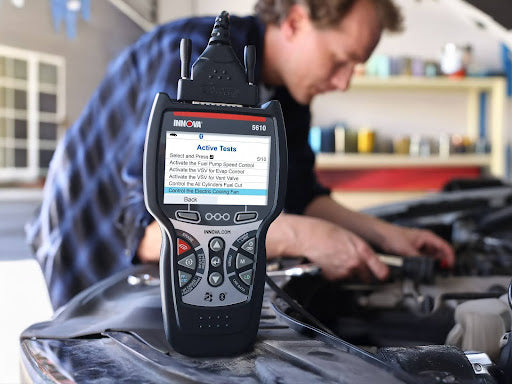 Man using advanced scanner tool Innova 5610 to diagnose vehicle issues.