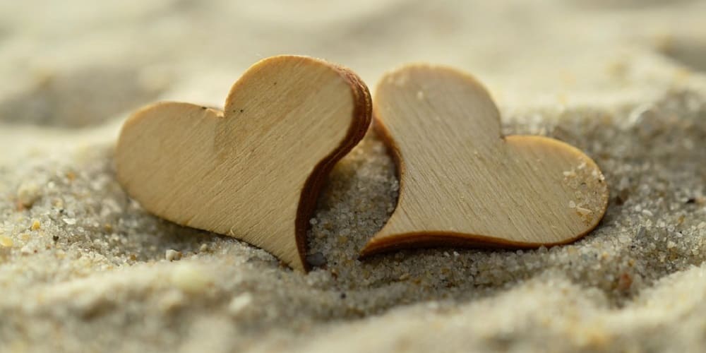 Coeur en bois sur le sable pour l'article Comment faire durer son couple - Les 8 conseils par insta-couple la boutique de tous les couples