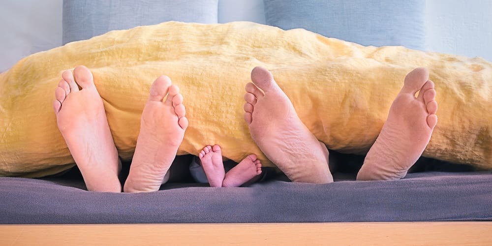 Pieds de Deux Adultes et un Bébé sous la Couette - L'Arrivée d'un Enfant dans un Couple - Insta-Couple