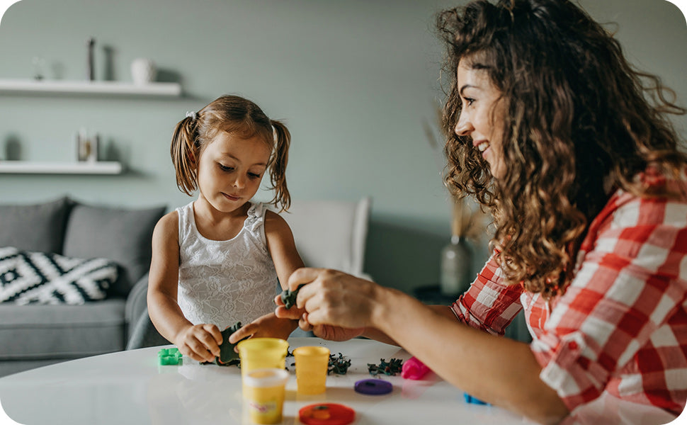 toddler girl playing with modeling clay with mother