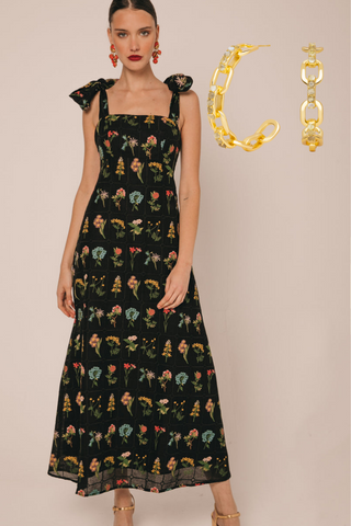 Vestido negro como look de boda de noche de primavera con flores con aros dorados grandes