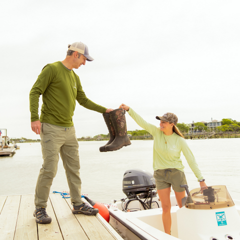 Man on dock and woman in boat in Lowcountry Land Trust shirts