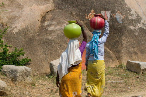 African women carrying water jugs on their heads.