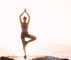 a person standing on one leg with her hands up in the air