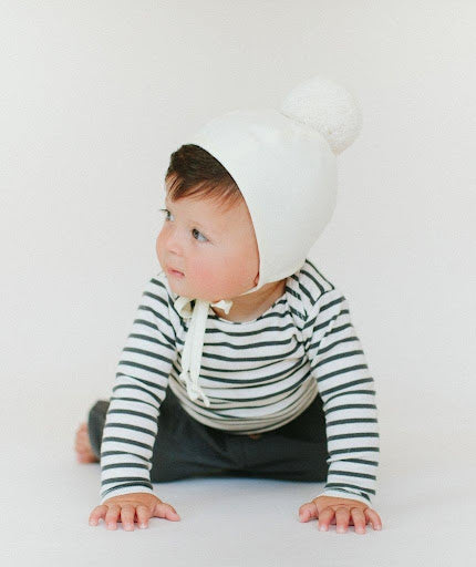 An image of a boy wearing the Ivory Pom Bonnet