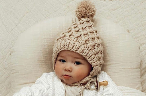 An image of a baby wearing a knitted baby bonnet 