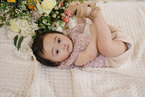 A baby wearing a ruffled floral bodysuit
