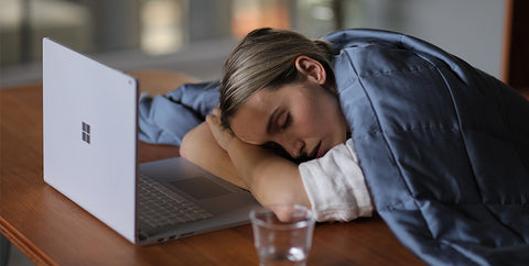 a lady is sleeping with a YNM cooling bamboo weighted blanket before her laptop