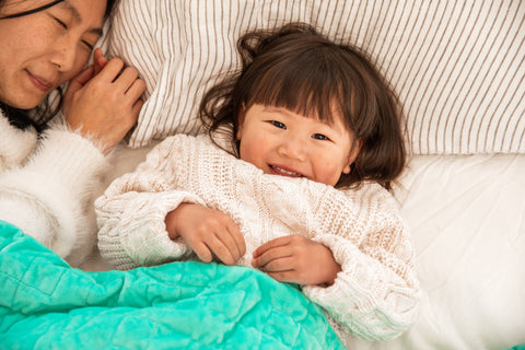 Child lying in bed with weighted blanket