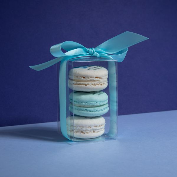 Small gift featuring white and blue macarons in a container wrapped with a blue bow at Oh La La! Macarons