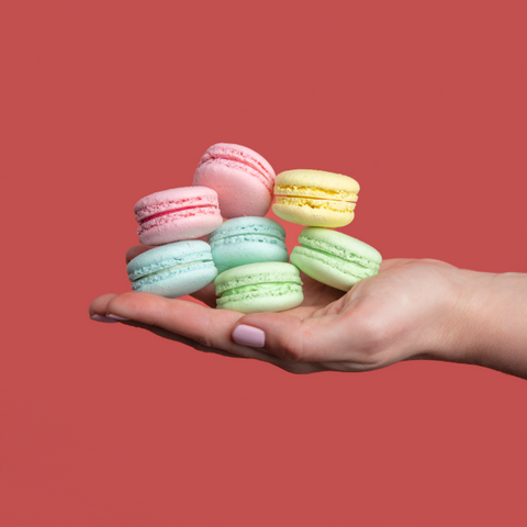 A hand holding an assortment of macarons at Oh La La! Macarons