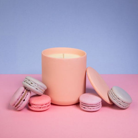 An assortment of macarons laying next to a pink Aery Candle at Oh La La! Macarons