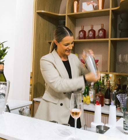 A woman shaking a martini at an Oh La La! Macarons event