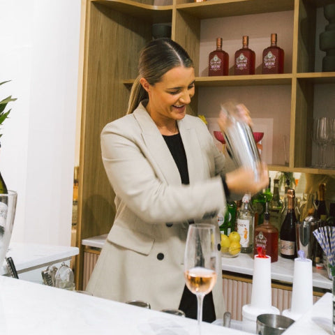 Business woman shaking up a martini behind the bar
