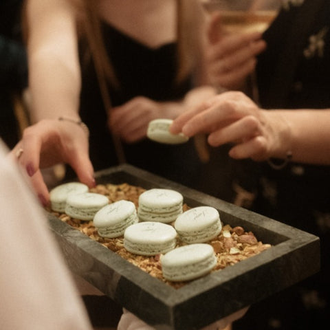 Women taking white macarons from a platter at Oh La La! Macarons