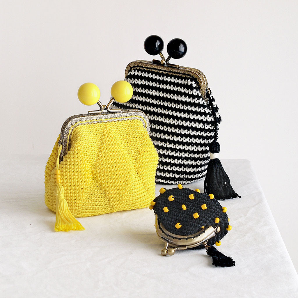 conjunto de tres monederos de crochet con cierre de boquilla de distinto tamaño y diseño en colores amarillo, blanco y negro