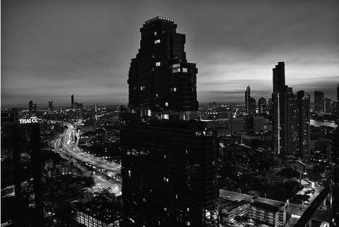 A high-rise shot of Bangkok city at night with a vibrant motorway below.