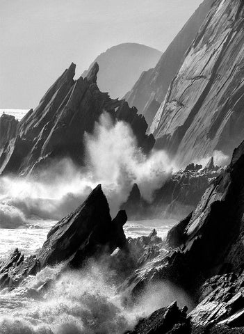 A black and white image of a jagged Dingle coastline with waves crashing against it. 