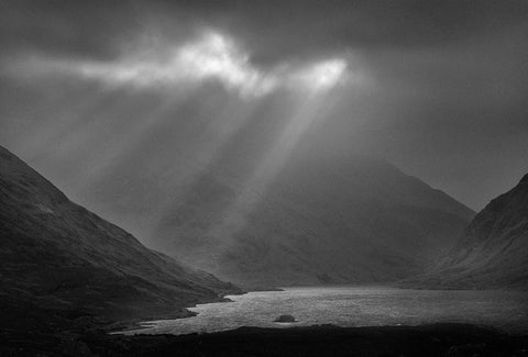 A black and white image of Doo Lough with sun rays shining down on it. 