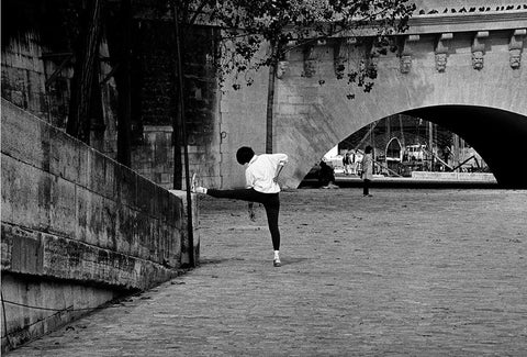 A woman stretching on a Parisian embankment. 