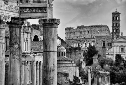 A black and white image of ancient Roman buildings with the Colosseum in the background.