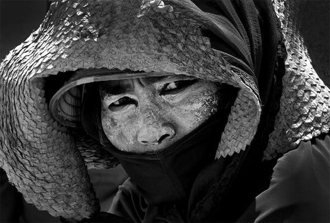 A black and white image of a Thai farm worker with thanaka on her face.