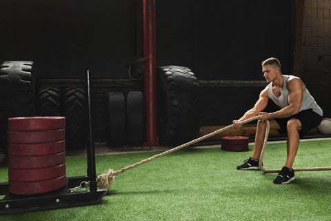 man performs a sled pull in the gym