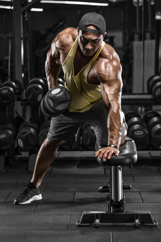 A man with muscles lifts dumbbells at a weight bench