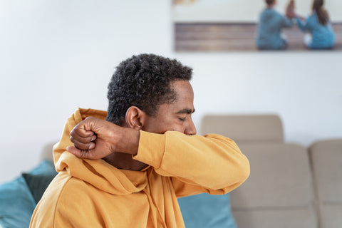 Man sneezing into his elbow