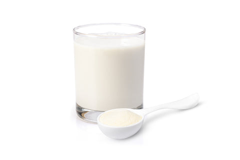 A scoop of whey protein powder next to a glass of milk