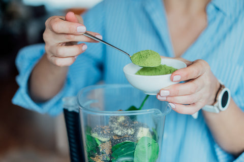 Vegan protein powder being added to a smoothie