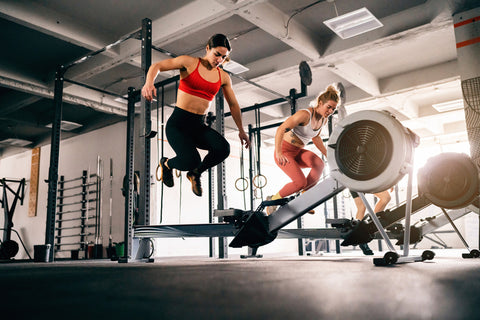 Women perform burpee broad jumps in the gym