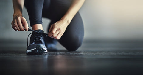 A close up of a woman tying her trainers