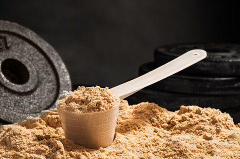 A scoop of whey protein powder on top of a pile of protein powder