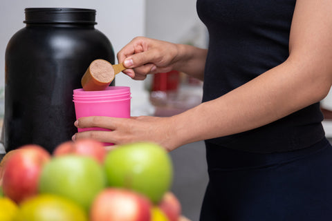 woman adds protein powder to her protein bottle