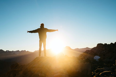 A man standing on a hill at sunset absorbing the sunlight and Vitamin D
