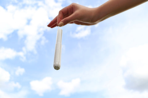 Hand holding tampon against sky