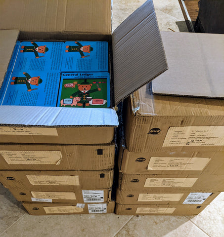 Two stacks of cardboard boxes containing accounting children's books