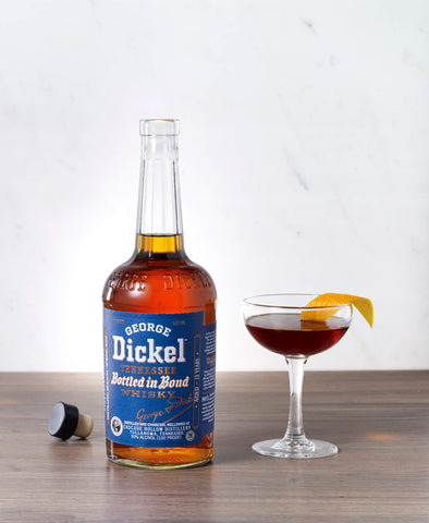 A bottle of George Dickel bottled in bond with an elegant Manhattan cocktail next to it.